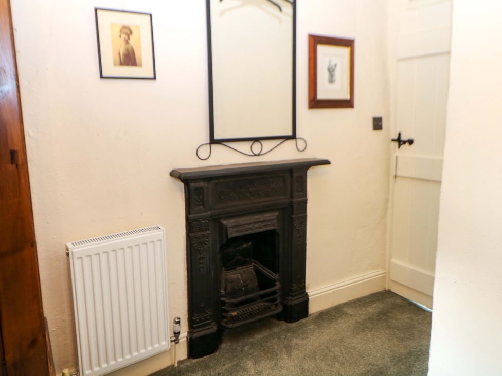 A hallway with a fireplace and mirror at Bargate Cottage in Hope Valley
