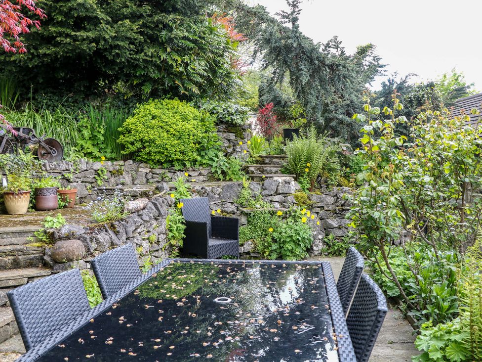 A garden with a stone wall and a table with chairs at Bargate Cottage Hope Valley