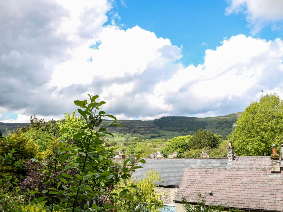 A view of mountains and houses under a cloudy sky at Bargate Cottage in Hope Valley