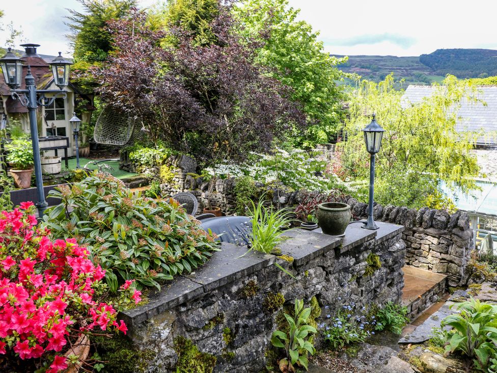 A garden with flowers and stone features at Bargate Cottage in Hope Valley