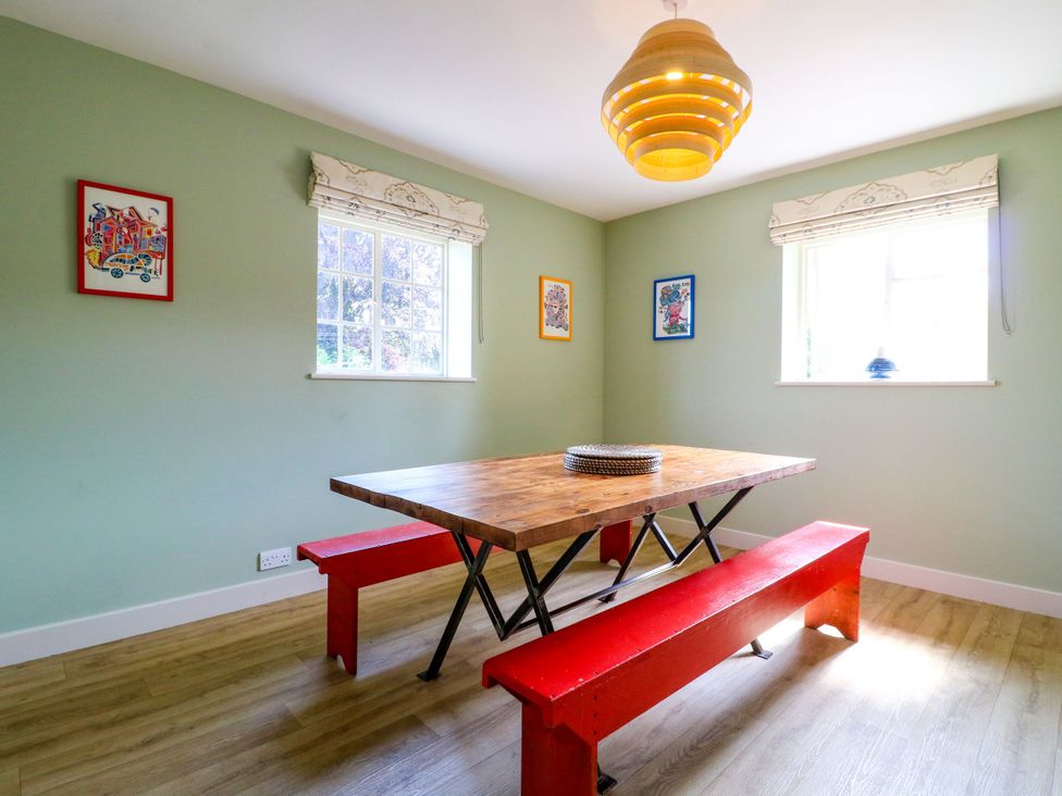 A dining room with a wooden table and red benches at The Stable Flat