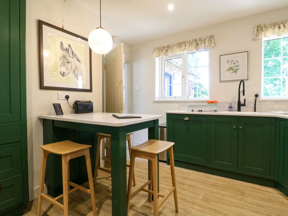 A kitchen featuring a table with stools and green cabinets at The Stable Flat