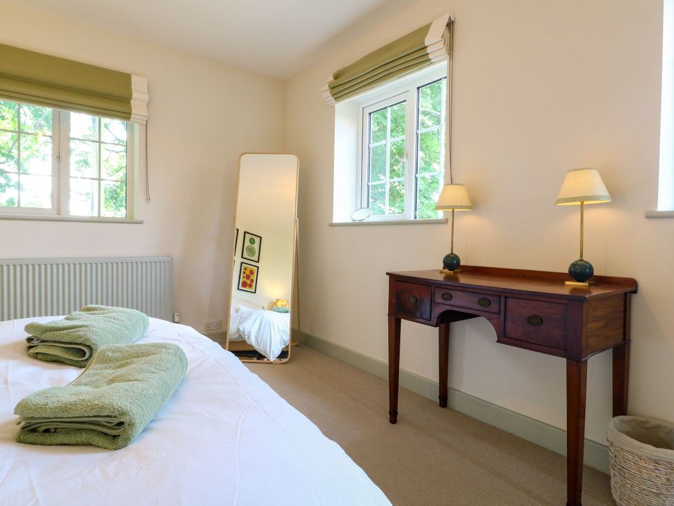 A bedroom with a bed, towels, mirror, table, and lamp at The Stable Flat 