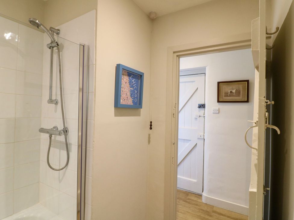 A bathroom with a shower and framed picture at The Stable Flat 