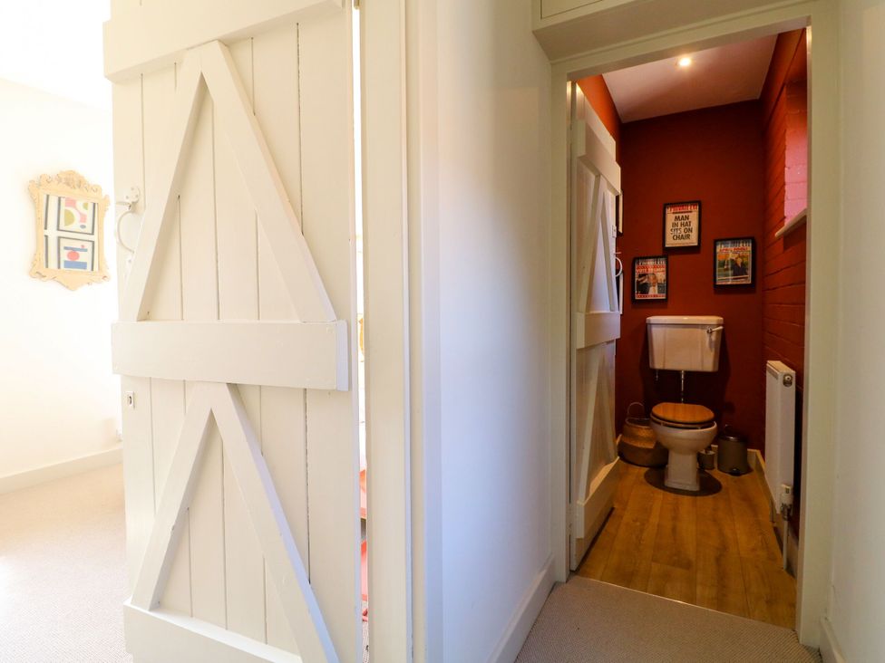 A bathroom with a toilet and framed pictures at The Stable Flat 