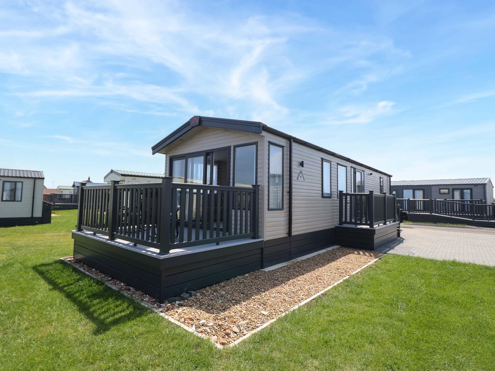 A mobile home with a deck and surrounding grass area at Sandy Shores Retreat in Norwich