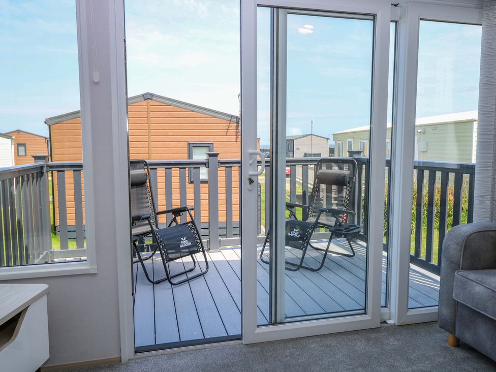 A living room with sliding doors leading to a balcony at Sandy Shores Retreat in Norwich