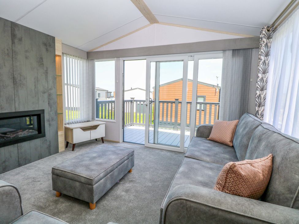 A living room with a fireplace and sliding doors at Sandy Shores Retreat in Norwich