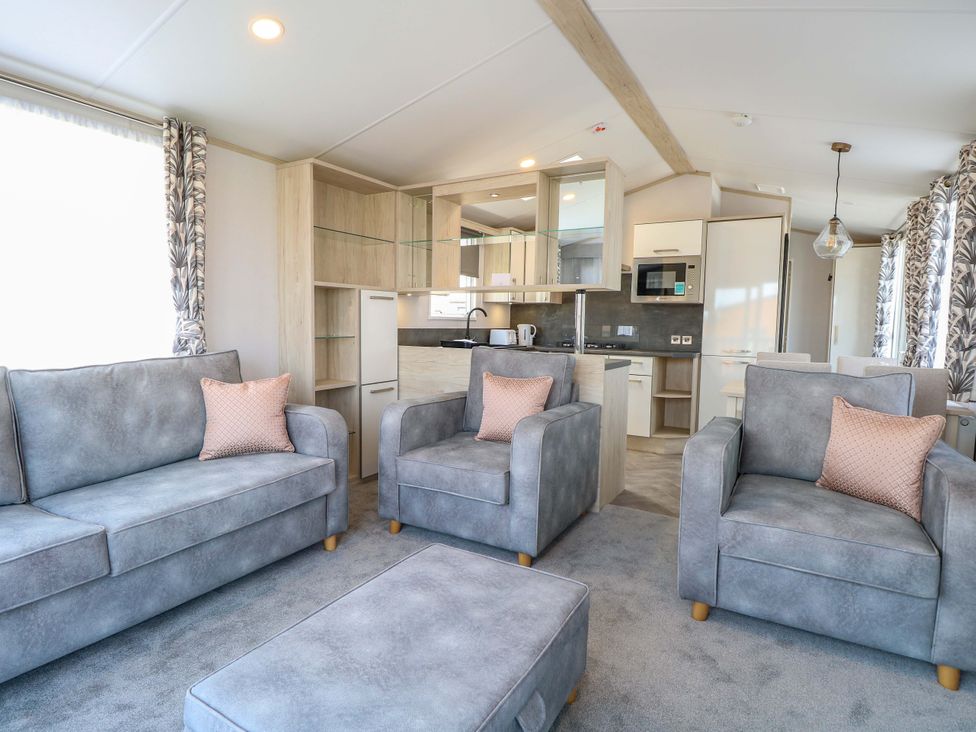 A living room with sofas and a kitchen area at Sandy Shores Retreat in Norwich