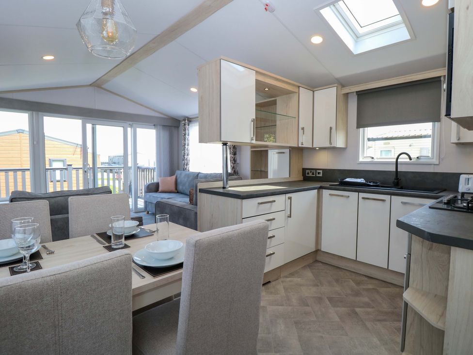 An open-plan living and dining area with kitchen cabinets at Sandy Shores Retreat in Norwich