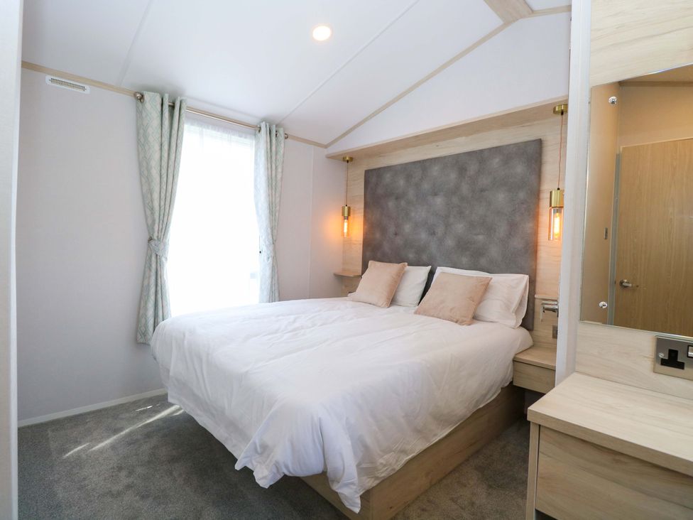 A bedroom with a bed and bedside table at Sandy Shores Retreat in Norwich