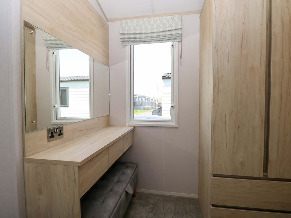 A bedroom with a dressing table and a mirror at Sandy Shores Retreat in Norwich