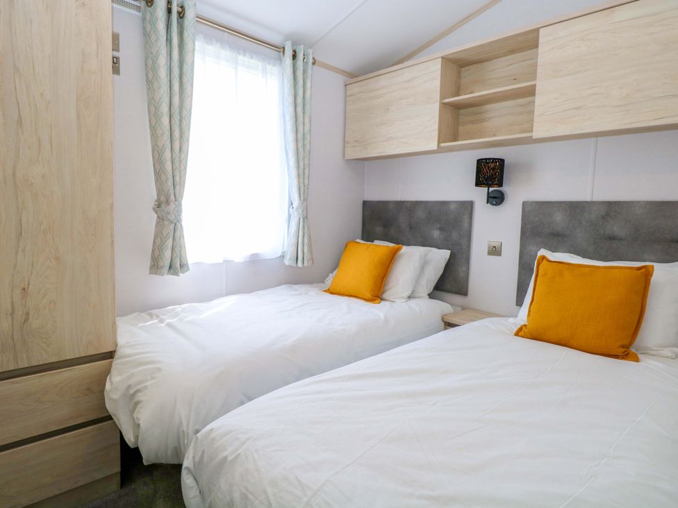A bedroom with two beds and a wardrobe at Sandy Shores Retreat in Norwich