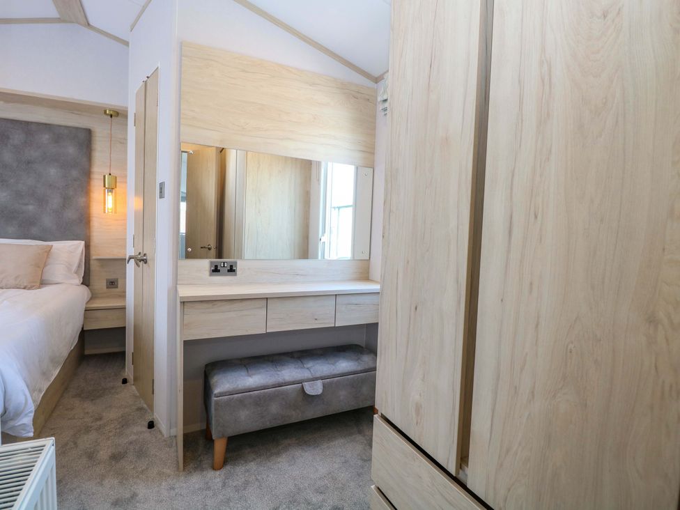 A bedroom with a bed and a vanity with a mirror at Sandy Shores Retreat in Norwich