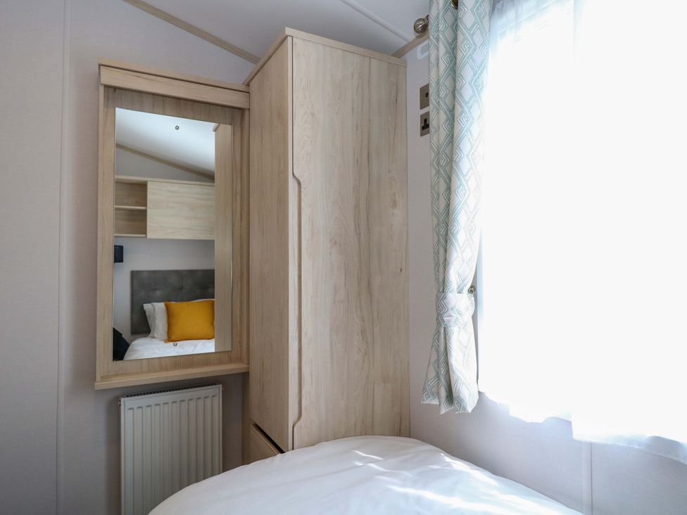 A bedroom with a mirror and wardrobe at Sandy Shores Retreat in Norwich