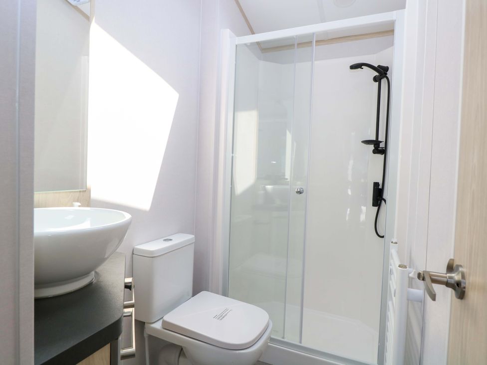 A bathroom with a shower, toilet, and wash basin at Sandy Shores Retreat in Norwich