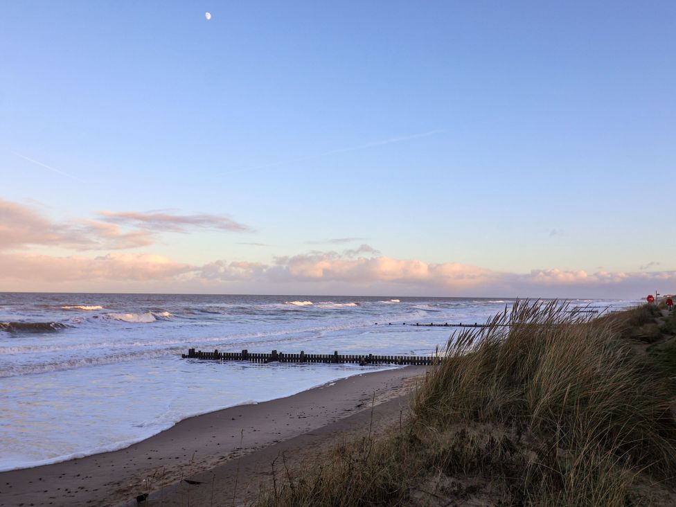 A beach with waves and sand at Sandy Shores Retreat in Norwich