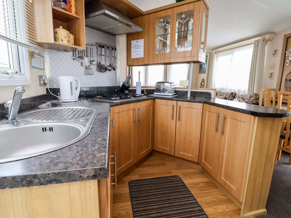 A kitchen with a sink, stove, kettle, and cupboards at Winchester - 478 Abergele