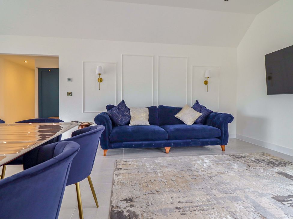 A living room with a sofa and dining chairs at Kingfisher