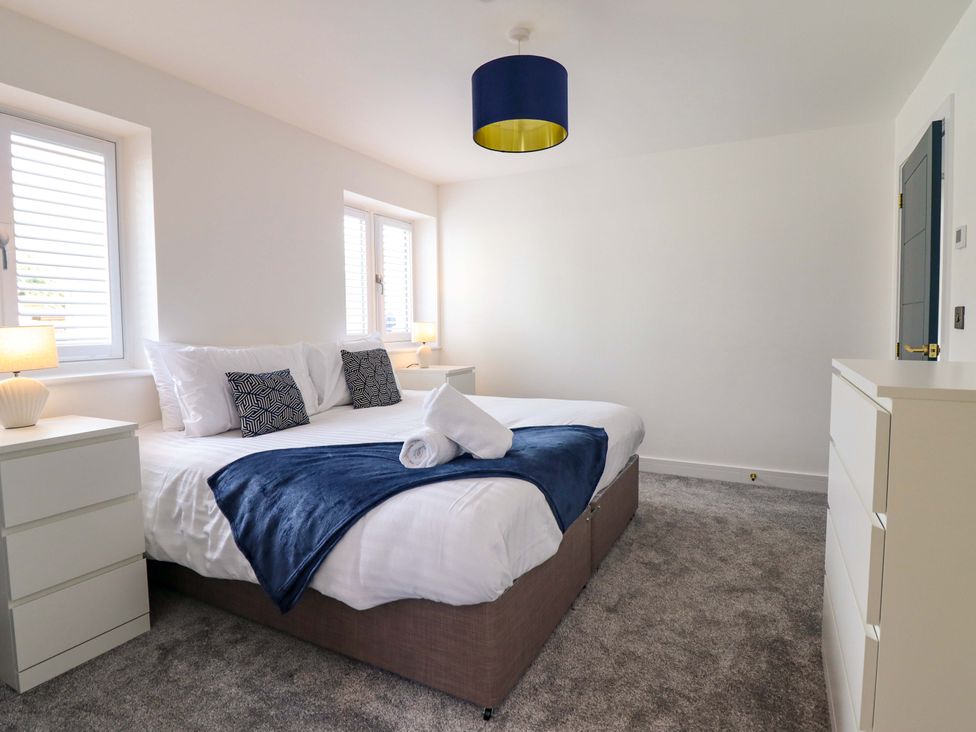 A bedroom with a bed and nightstands at Kingfisher