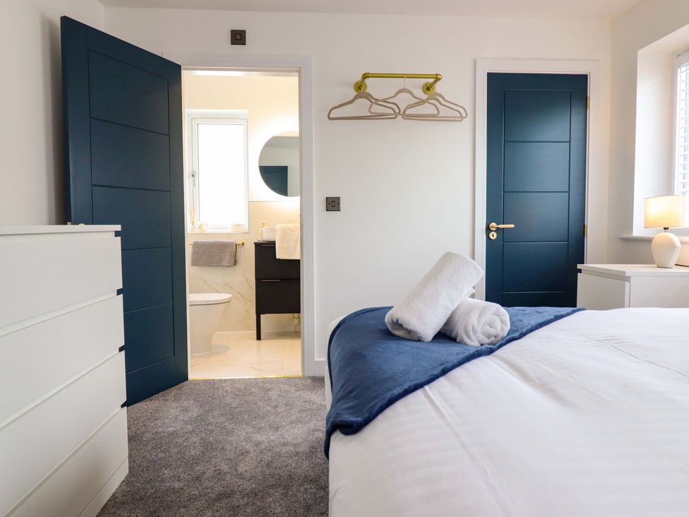 A bedroom with a bed, dresser, and access to adjacent bathroom at Kingfisher