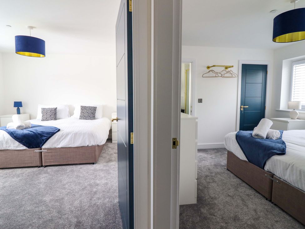 A bedroom with two beds and a lamp at Kingfisher