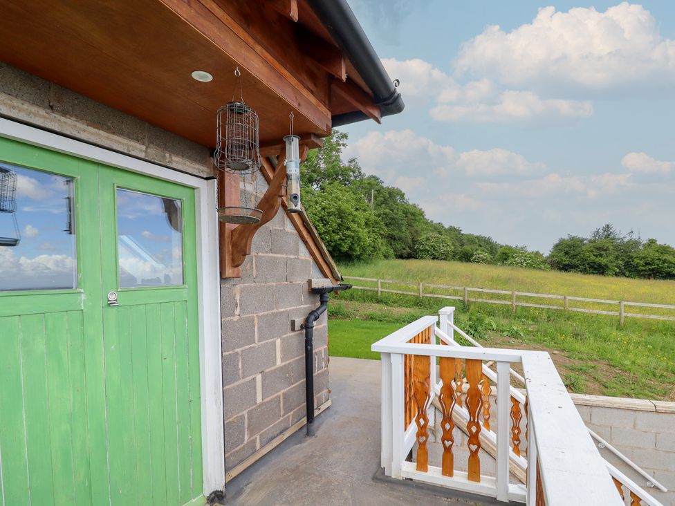 A view of an exterior area with a green door and bird feeders at Hay Loft at Ebenezer Chapel Milwr