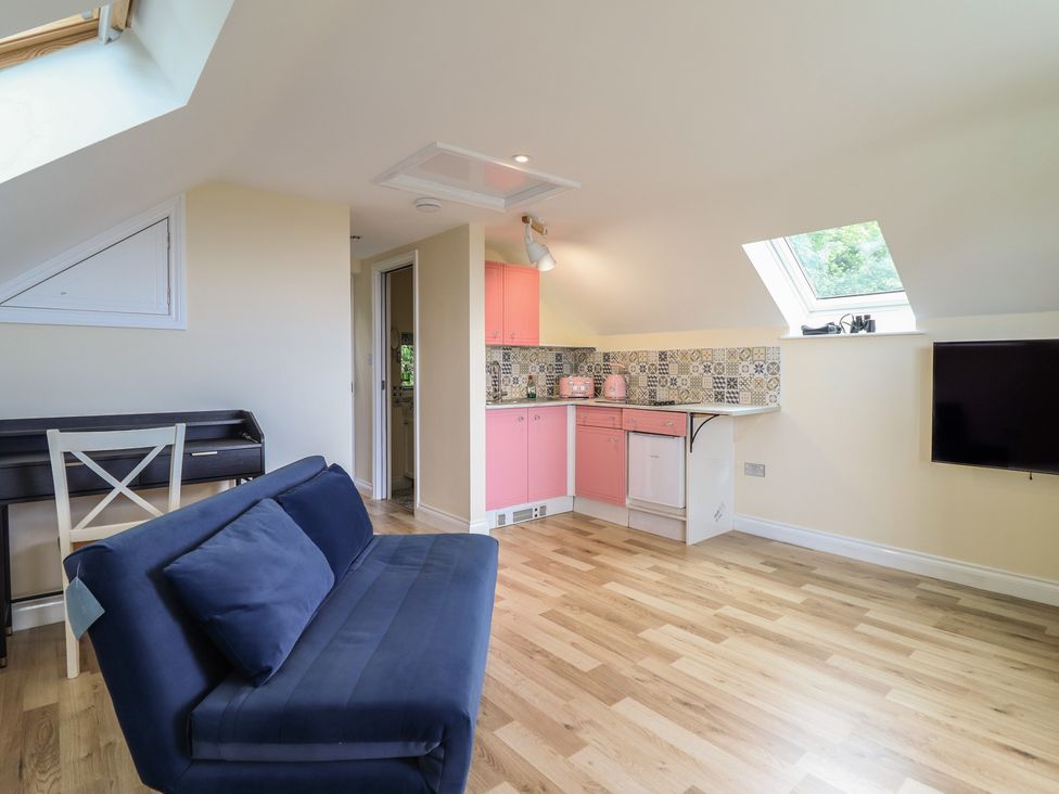 A living room with a kitchen area and a sofa at Hay Loft at Ebenezer Chapel Milwr