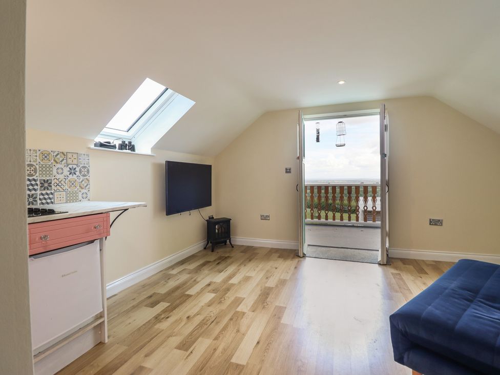 An attic room with a television and balcony doors at Hay Loft at Ebenezer Chapel Milwr