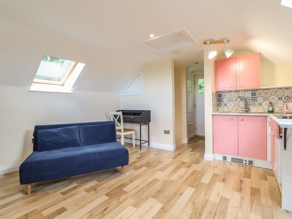 A living room with a sofa and kitchen units at Hay Loft at Ebenezer Chapel in Milwr