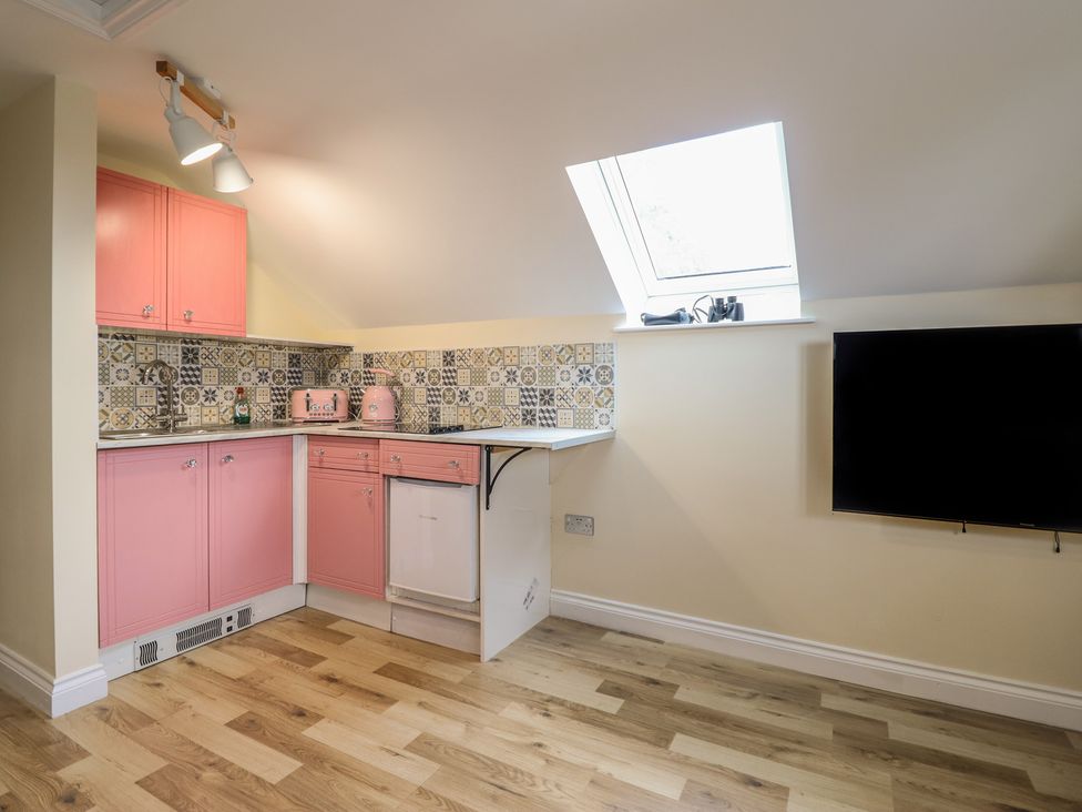 A kitchen with pink cabinets and patterned tiles at Hay Loft at Ebenezer Chapel in Milwr