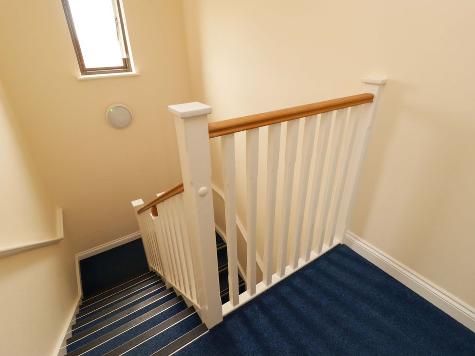 A staircase with a railing and window at Twyni Bach