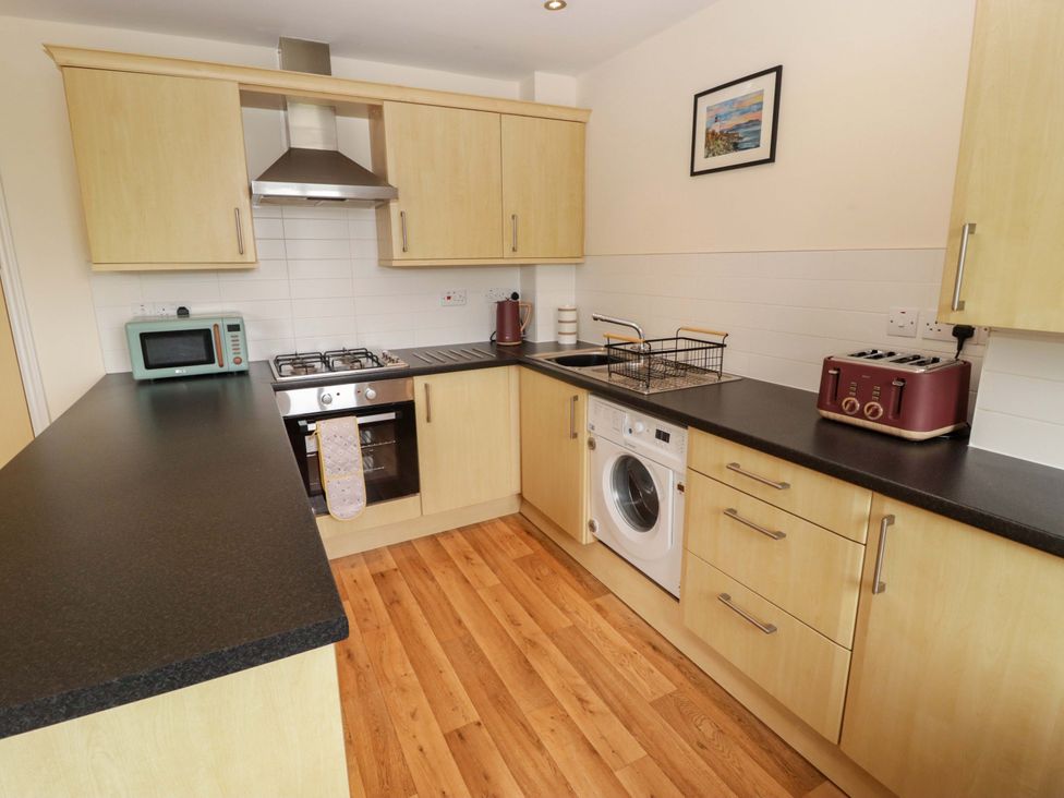 A kitchen with microwave, oven, washing machine at Twyni Bach in 