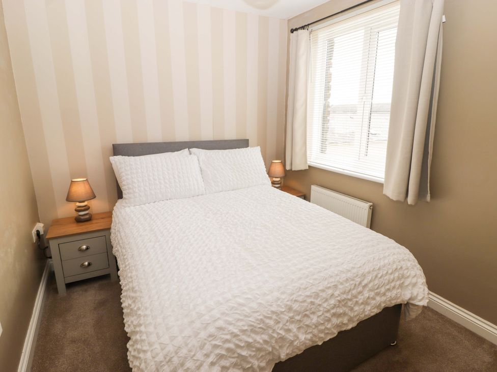 A bedroom with a double bed and side lamps at Twyni Bach