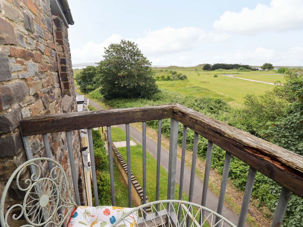 A balcony with a bistro table and chairs overlooking grassy fields at Twyni Bach in 