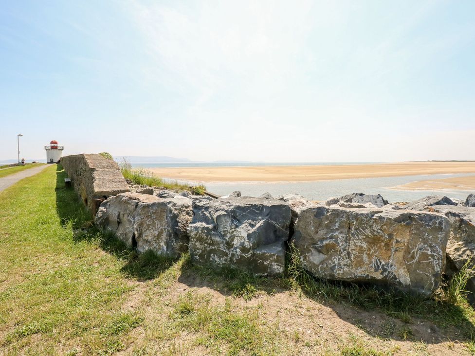 A coastal view with rocks and a lighthouse at Twyni Bach