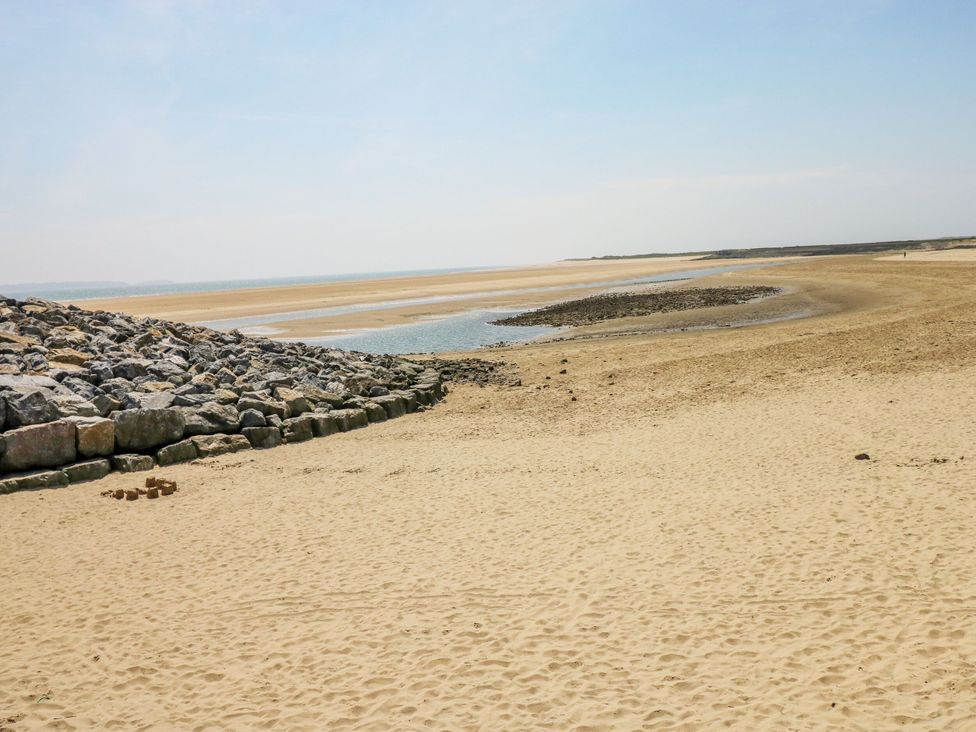 A beach with sand and rocks near water at Twyni Bach
