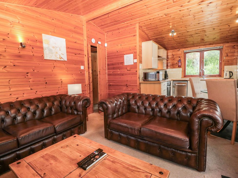 A living room with brown sofas and a kitchenette at 89 Ambleside in White Cross Bay