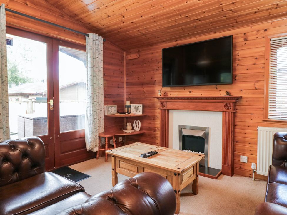 A living room with a television above a fireplace at 89 Ambleside in White Cross Bay