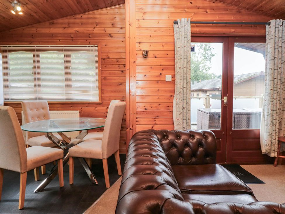 A dining area with a glass table and chairs at 89 Ambleside White Cross Bay