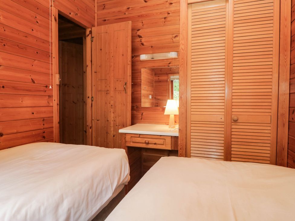 A bedroom with two beds and a desk with a lamp at 89 Ambleside in White Cross Bay