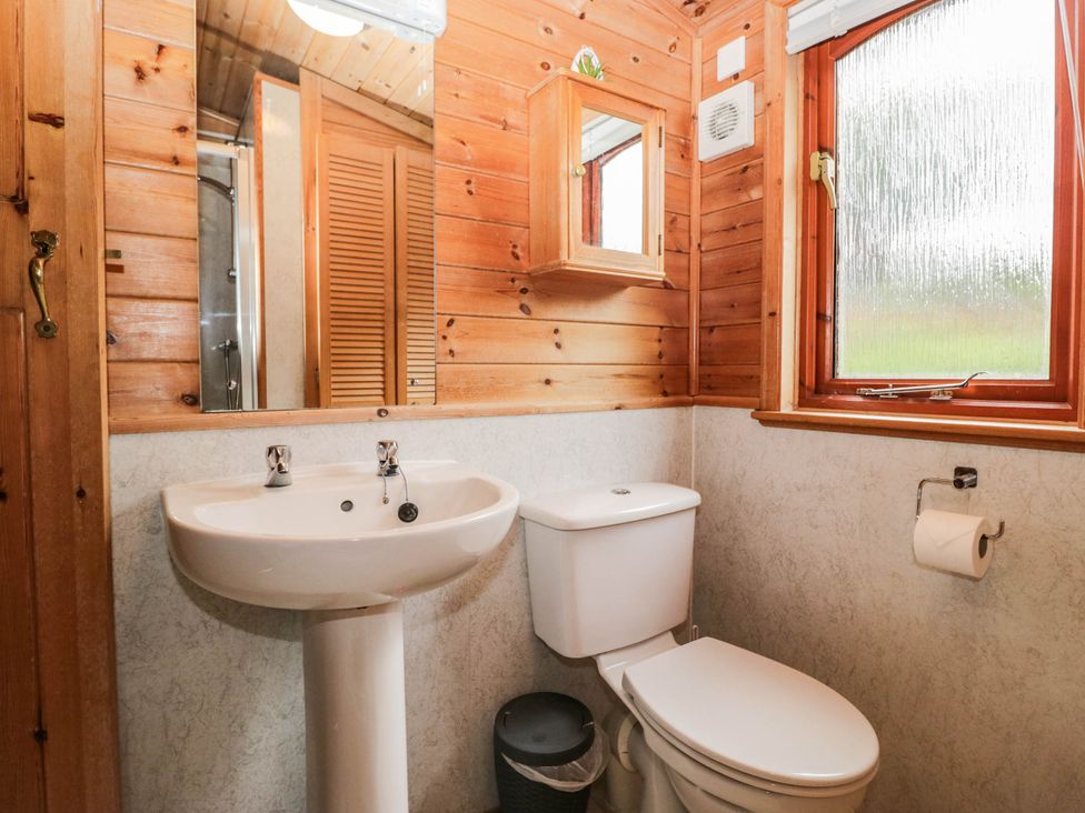 A bathroom with a sink, toilet, and window at 89 Ambleside in White Cross Bay
