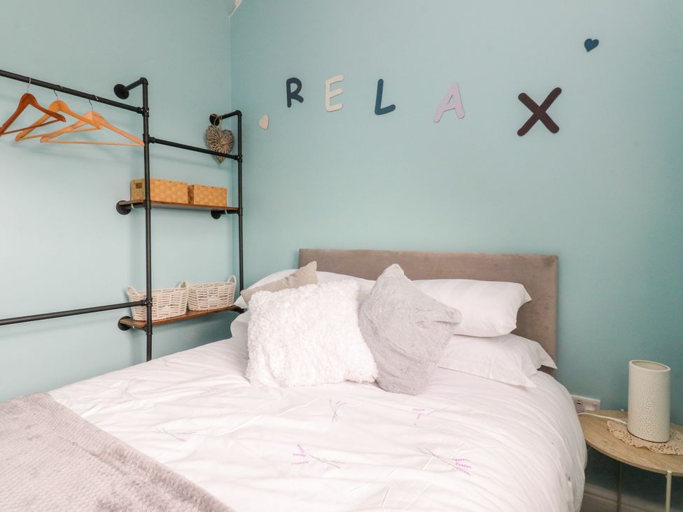 A bedroom with a bed and shelf displaying storage baskets at The View in Ilkley