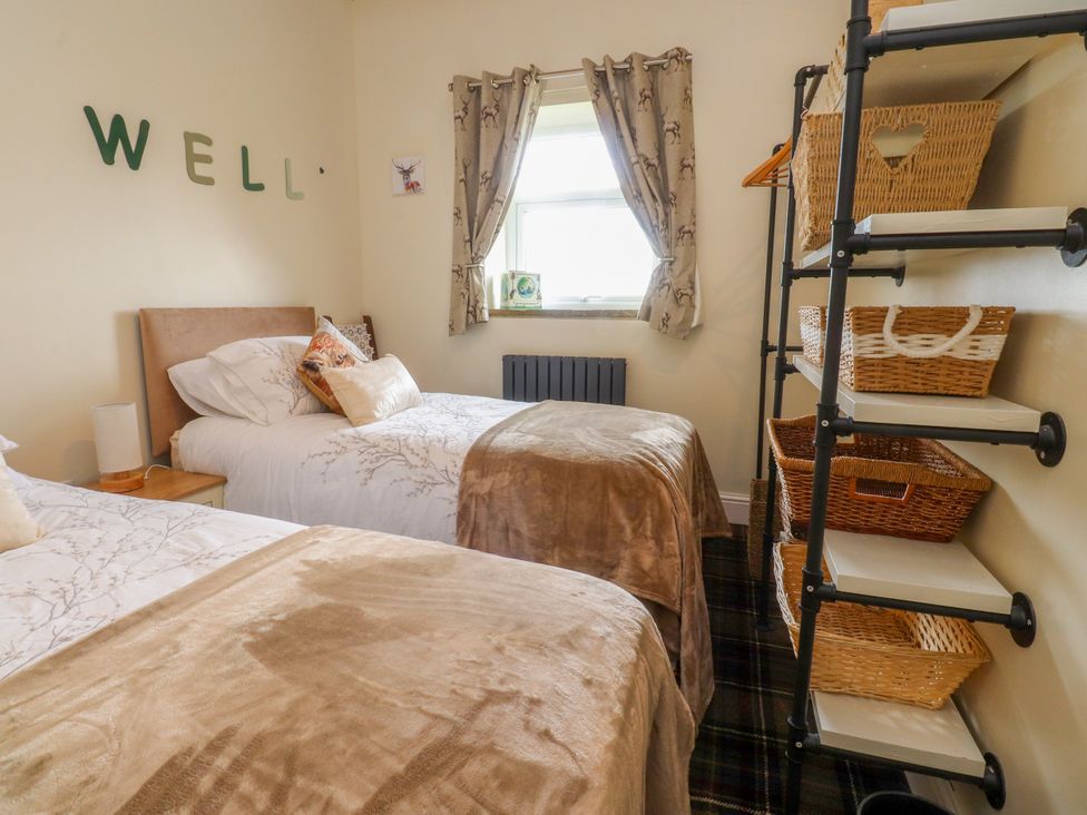 A bedroom with two beds and a shelf containing baskets at The View in Ilkley