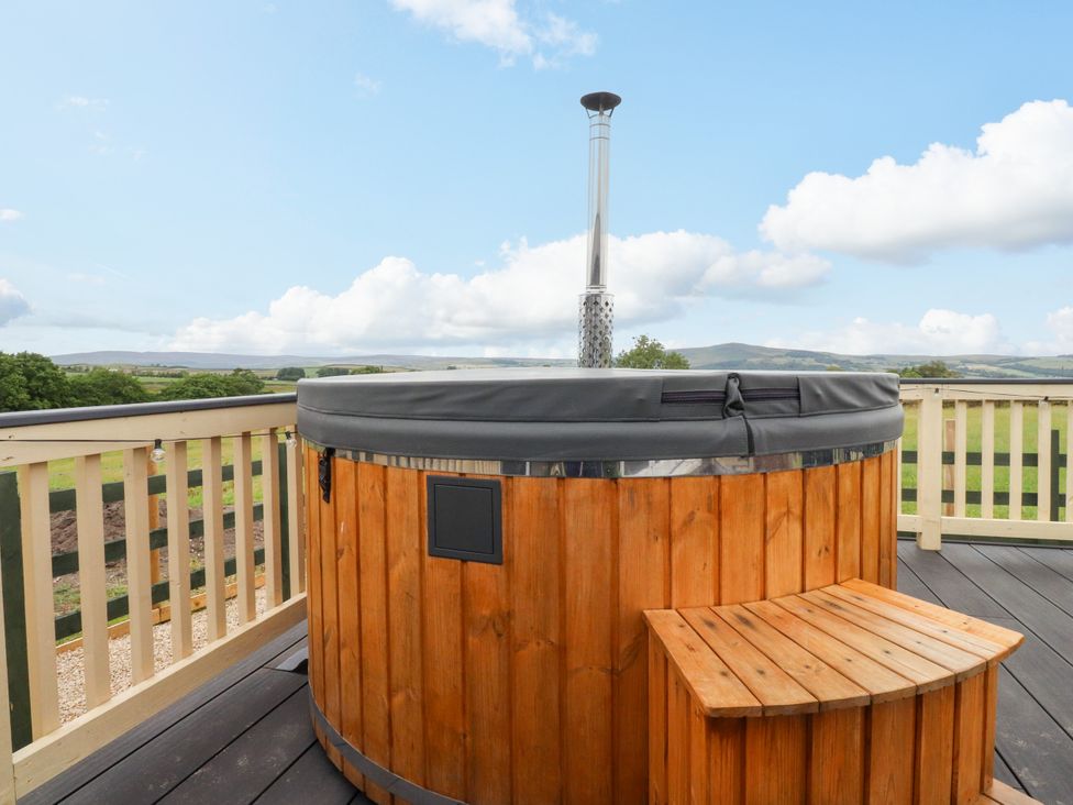 A hot tub with a wooden bench on an outdoor deck at The View Ilkley