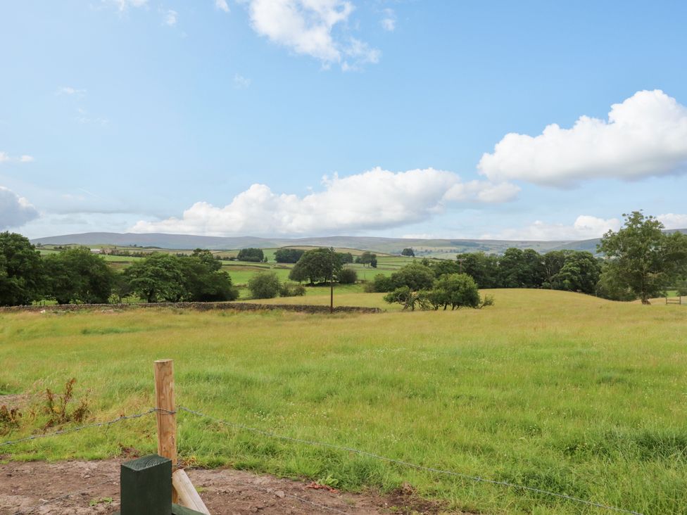 A grassy field with trees and hills at The View in Ilkley