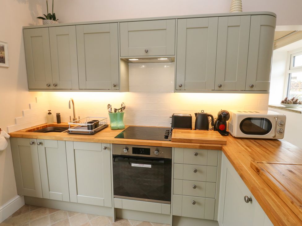 A kitchen with cabinets, sink, cooker, and microwave at The View near Addingham