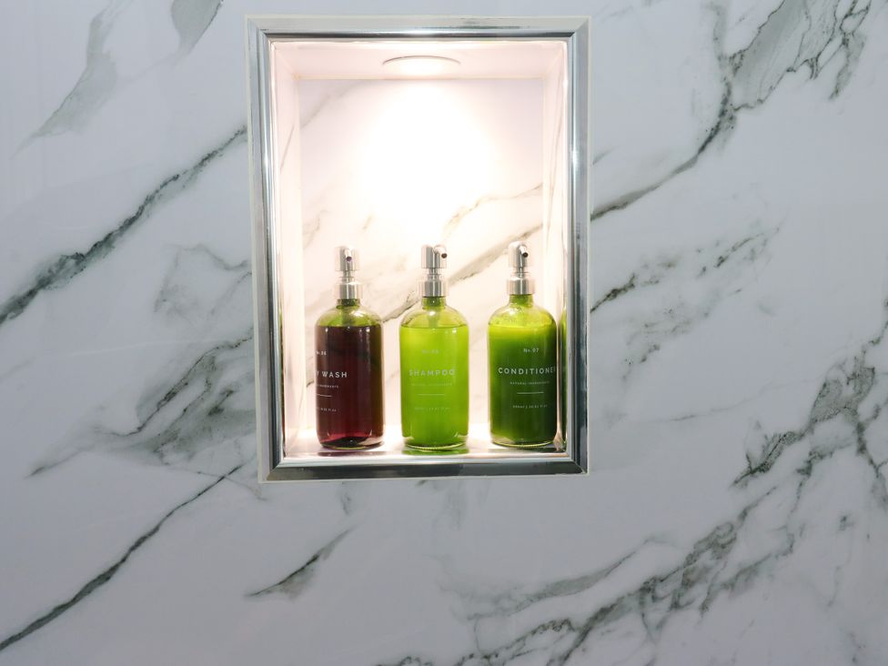 A bathroom shelf with three bottles of wash, shampoo, and conditioner at The View near Addingham
