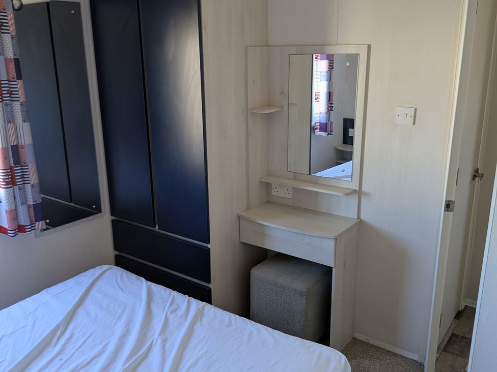 A bedroom with a bed, mirror, and dresser at Presthaven - Denbigh Dunes, Prestatyn