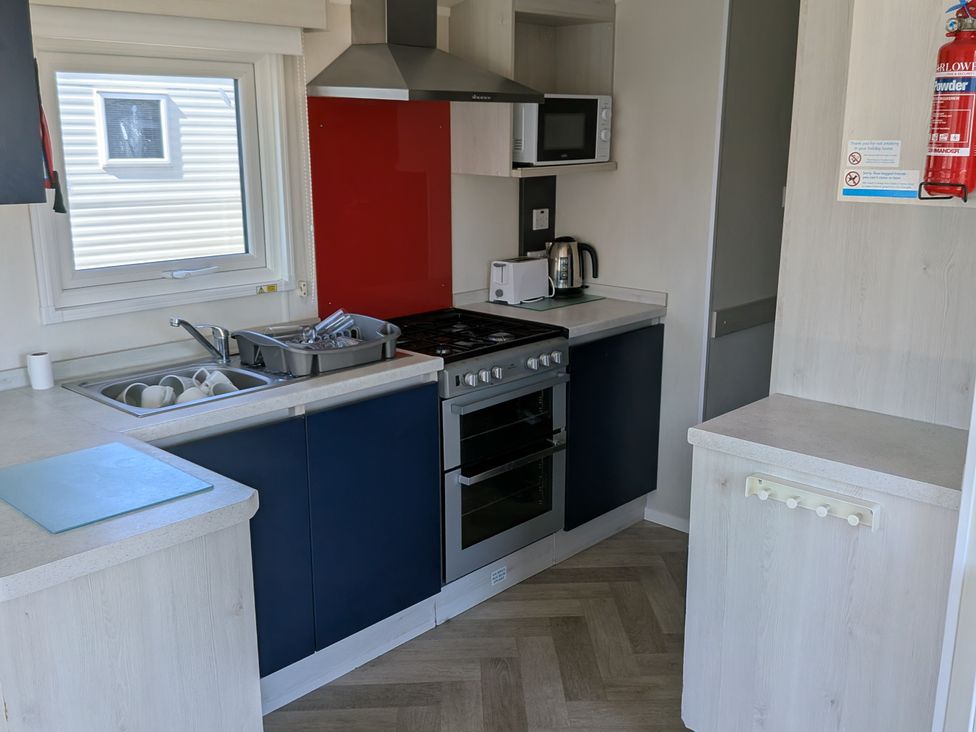 A kitchen with a stove, oven and microwave at Presthaven - Denbigh Dunes, Prestatyn
